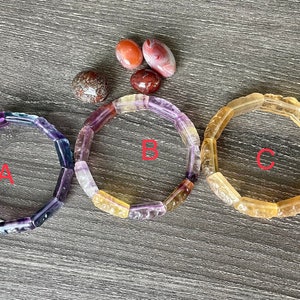 May include: Three bracelets made of faceted gemstone beads. The bracelets are labelled A, B, and C. Bracelet A is purple, blue, and green. Bracelet B is yellow, orange, and purple. Bracelet C is yellow.