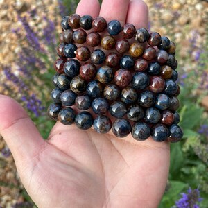 May include: A stack of eight bracelets made of blue and brown tiger's eye beads.