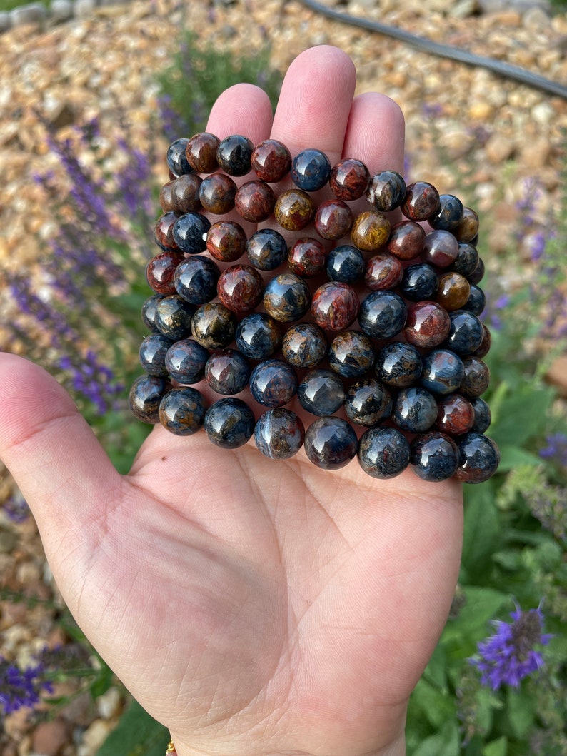 May include: A stack of eight bracelets made of blue and brown tiger's eye beads.