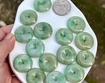 May include: A collection of 15 jade green round beads with a hole in the center. The beads are arranged on a white plate. A US quarter is included for size reference.