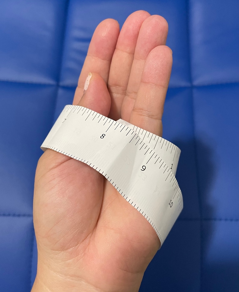 May include: A white measuring tape wrapped around a hand, showing measurements from 7 to 10 inches.