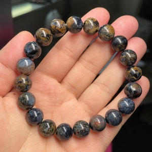 May include: A bracelet made of round, dark blue and brown tiger's eye beads.