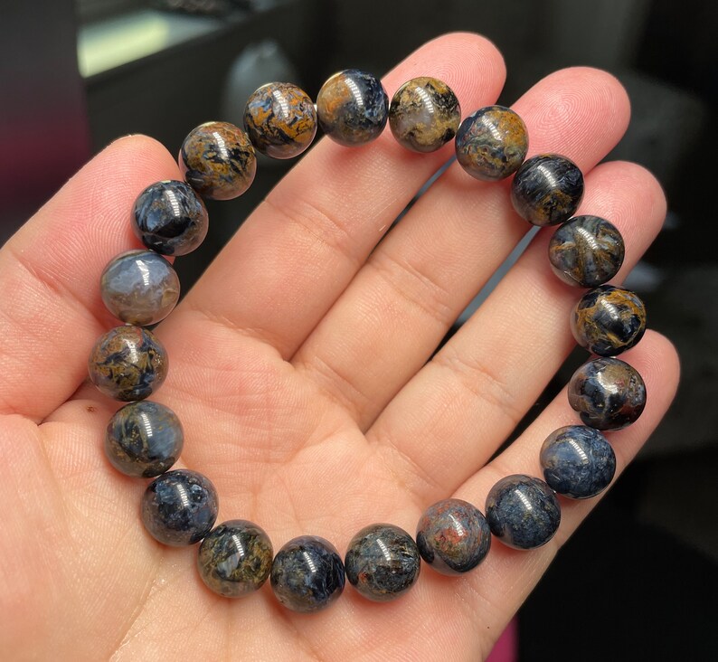 May include: A bracelet made of round, dark blue and brown tiger's eye beads.