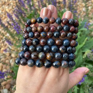 May include: A stack of eight bracelets made of blue, brown, and gold tiger's eye beads.