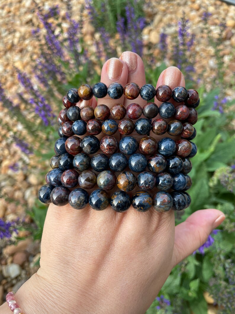May include: A stack of eight bracelets made of blue, brown, and gold tiger's eye beads.