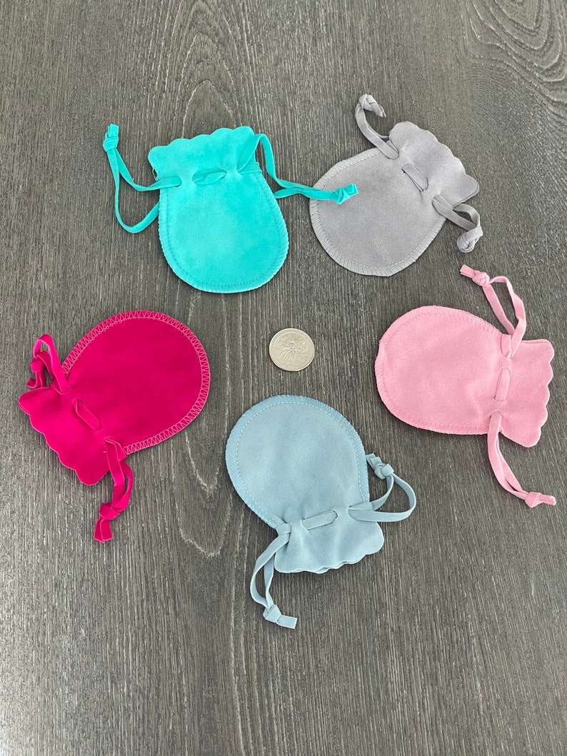 Puede incluir: Cinco peque&ntilde;as bolsas de cord&oacute;n en diferentes colores: turquesa, gris, rosa, azul claro y rojo. Las bolsas est&aacute;n hechas de un material suave y aterciopelado y tienen un borde festoneado.