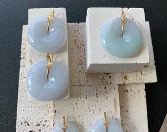 May include: Four jade pendants with gold star charms. The pendants are round and flat, with a hole in the center. They are displayed on a white textured surface.