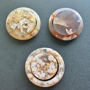 Puede incluir: Tres posavasos redondos de piedra pulida con diseños únicos. Los posavasos presentan una variedad de colores, incluyendo beige, marrón y blanco, con intrincados diseños naturales. Los posavasos están hechos de un material translúcido, ideal para la decoración del hogar.