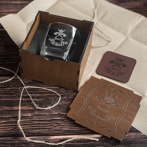 May include: A wooden box with a clear glass etched with the words "Jears Of The Pillaged" and a Viking helmet and crossed axes design. The box is open and the glass is inside. There is a smaller wooden box with the same design and a brown leather coaster with the same design.