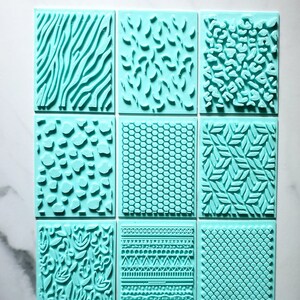 May include: Nine turquoise blue polymer clay stamps with different patterns, including zebra stripes, leaves, and geometric designs. The stamps are arranged in three rows of three. The text "Blessed Eli Polymer Clay Jewelry" is visible at the bottom of the image.