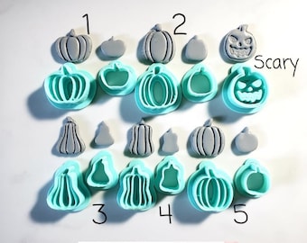 May include: Set of 15 grey and teal plastic pumpkin and gourd cookie cutters. The cutters are numbered 1 through 5. The cutters are arranged in rows. The text "Scary" is written in white on a black background. The text "Blessed Eli" is written in black on a white background.