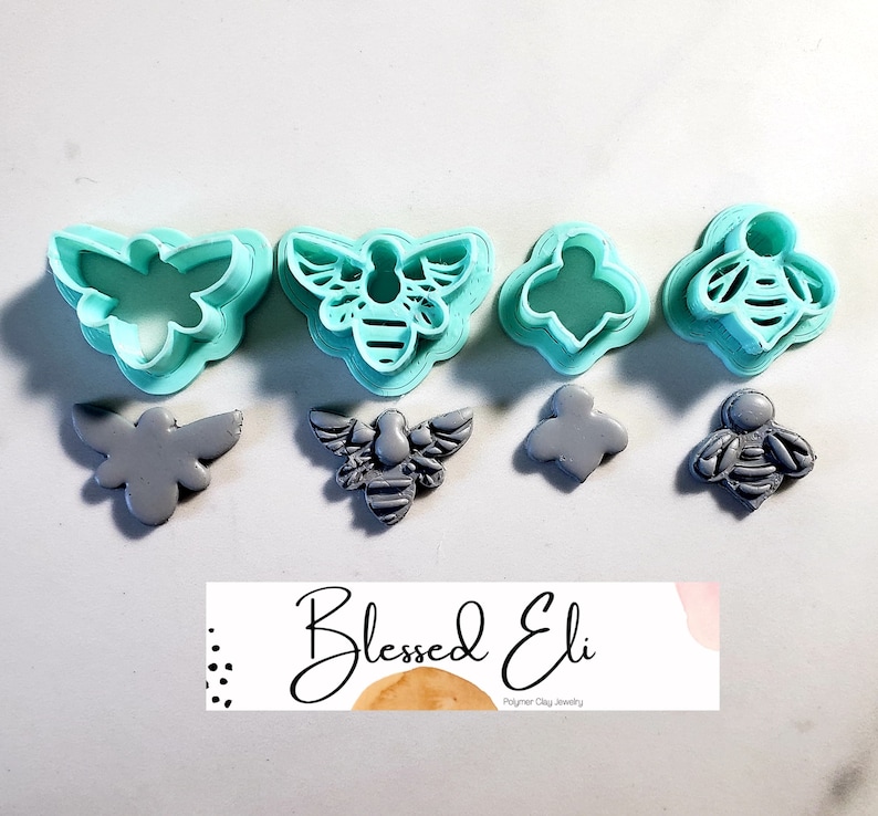 May include: Set of four bee-themed polymer clay cutters and four gray polymer clay bee shapes. The cutters are turquoise blue and the bee shapes are gray. The cutters are in the shape of a bee, a bee with wings, and a bee with a honeycomb pattern. The bee shapes are in the same shapes as the cutters. The image also includes a small business logo that says "Blessed Eli Polymer Clay Jewelry".