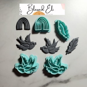 May include: A set of eight polymer clay cookie cutters, including two rainbow arches, two birds, and four feathers. The cutters are in two colors: gray and teal.