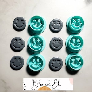 May include: Set of 10 smiley face cookie cutters, 5 in teal blue and 5 in gray. The cutters feature different smiley face expressions, including winking, hearts, stars, and Xs.