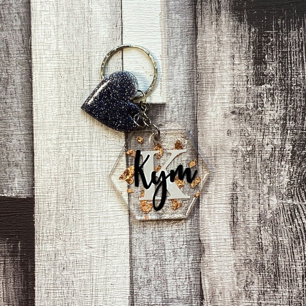 Rose gold detailed personalised acrylic key ring with black glitter heart. Clear hexagon with black name and white initial detailing