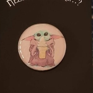 Puede incluir: Un botón redondo con una imagen de dibujos animados de un personaje extraterrestre verde sosteniendo un cono de helado rosa. El botón está en una tarjeta negra con el texto "NEEDLE SAY MORE...?" y "THANK YOU!"