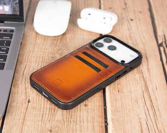 May include: A black smartphone case featuring a tan and brown gradient leather back panel with two integrated card slots. The case has a black frame, precise cutouts for the camera lenses, and a small embossed logo on the lower leather section.