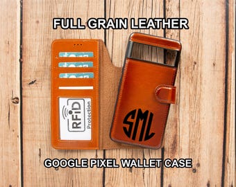 May include: A tan full grain leather wallet case for a Google Pixel phone. The interior features three card slots and a clear ID window with RFID protection text. The exterior cover displays a black circular monogram with the letters SML.