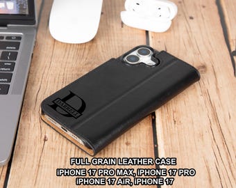 May include: Black full-grain leather phone case with the name "DARRELL" and a large initial "D" printed on the front. The case is designed for iPhone 17 Pro Max, 17 Pro, 17 Air, and 17 models. A laptop, mouse, and earbuds are in the background.