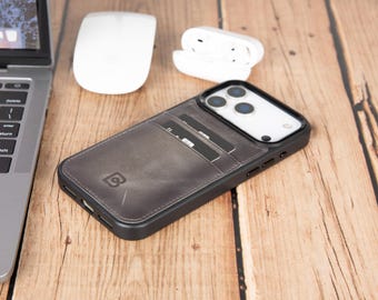 May include: A dark gray smartphone case with a built-in card holder slot on the back, featuring a black frame and a visible logo. The case is designed with a smooth, leather-like texture and includes cutouts for the camera lenses and side buttons.