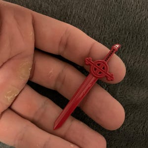 May include: A red plastic sword with a cross-shaped handle and the word "VAMPIRES" written on the blade.