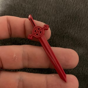 May include: A red plastic sword with a Celtic knot design on the hilt.