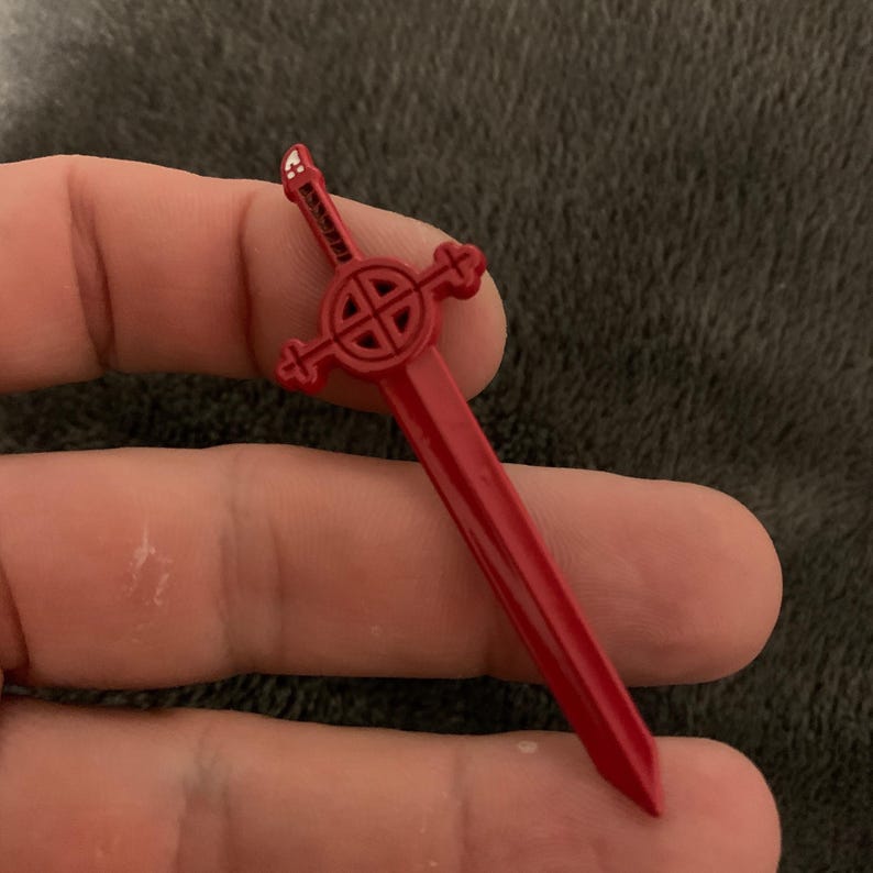 May include: A red plastic sword with a Celtic knot design on the hilt.