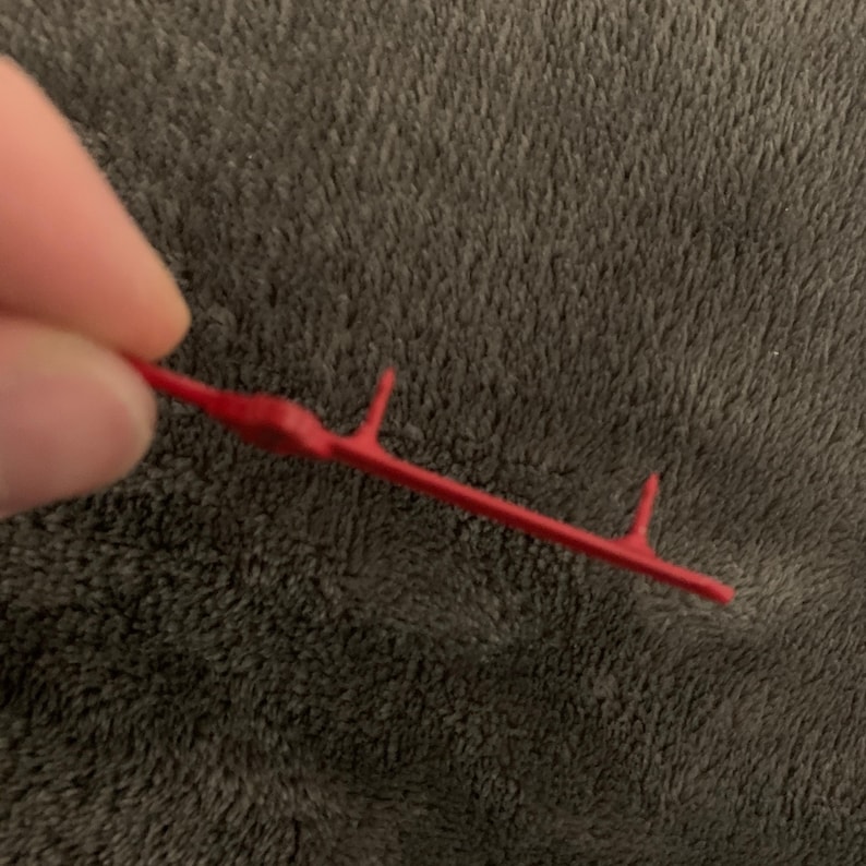 May include: A red plastic tool with four prongs, used for attaching or removing items.