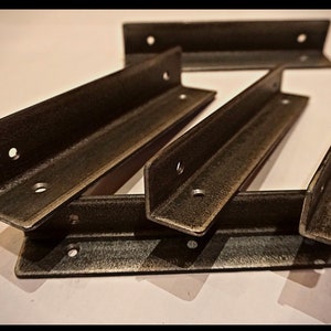 May include: Five metal shelf brackets in a dark brown finish. The brackets are L-shaped and have multiple holes for mounting.