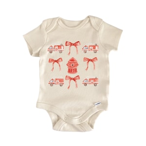 May include: A cream-coloured baby onesie with a watercolour design of red fire engines, bows, and a fire hydrant. The short-sleeved bodysuit has a snap closure and is made of soft fabric.