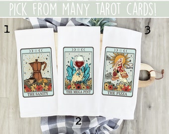 May include: Three kitchen towels with a tarot card design. The first towel features a coffee pot and the text "THE SANITY". The second towel features a glass of wine and the text "THE MEGA PINT". The third towel features a slice of pizza and the text "THE PIZZA".