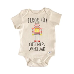 Peut inclure: Un body de bébé crème avec le texte "ERROR 404" au-dessus d'une illustration de robot rouge, jaune et argenté. En dessous du robot, le texte "CUTENESS OVERLOAD". Le body a des manches courtes et des boutons-pression en bas.