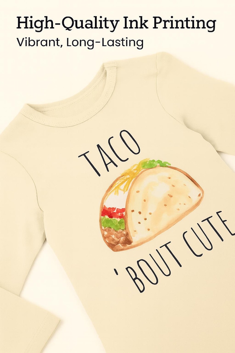 A beige long-sleeved t-shirt with a printed design of a taco and the text "TACO 'BOUT CUTE" printed on it.