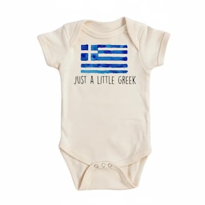 Op de afbeelding: Crème babybody met een Griekse vlag in aquarel blauw. De tekst "JUST A LITTLE GREEK" staat eronder. De body heeft korte mouwen en drukknoopsluitingen.