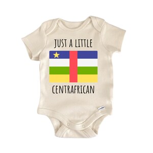 May include: A cream-colored short-sleeve baby bodysuit featuring the text "JUST A LITTLE" above the flag of the Central African Republic and the word "CENTRAFRICAN" below it. The flag design includes blue, white, green, and yellow horizontal stripes with a vertical red stripe and a yellow star.