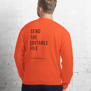 May include: Bright orange sweatshirt with the text "SEND THE EDITABLE FILE" in black, with "EVERYDAY HEROES CO." below. The sweatshirt is a solid colour and has long sleeves.