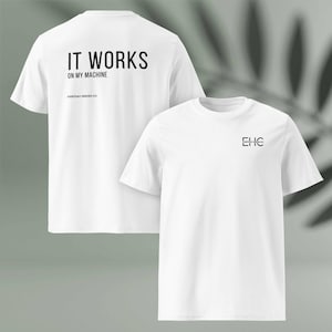以下が含まれることがあります： 2つの白いTシャツ。1つのシャツには、背面に黒で「IT WORKS ON MY MACHINE」と「EVERYDAY HEROES CO.」とプリントされています。もう1つのシャツには、前面に黒で「EHC」の文字がプリントされています。