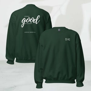 May include: Two dark green sweatshirts. One features the text "it looked good on my screen" and "EVERYDAY HEROES CO." in white. The other has "EHC" in white on the chest. Both have a crew neck and long sleeves.