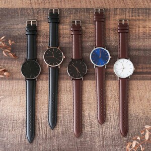 four watches are lined up on a wooden surface