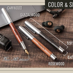 a wooden table topped with a laptop computer and a pen