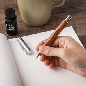 a person holding a pen and writing on a piece of paper