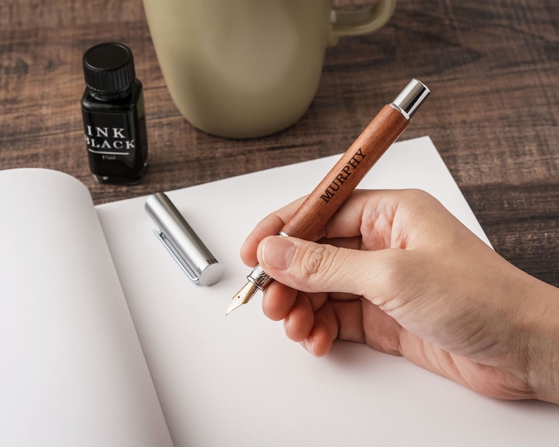 a person holding a pen and writing on a piece of paper