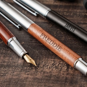 three pens and a pen on a wooden table