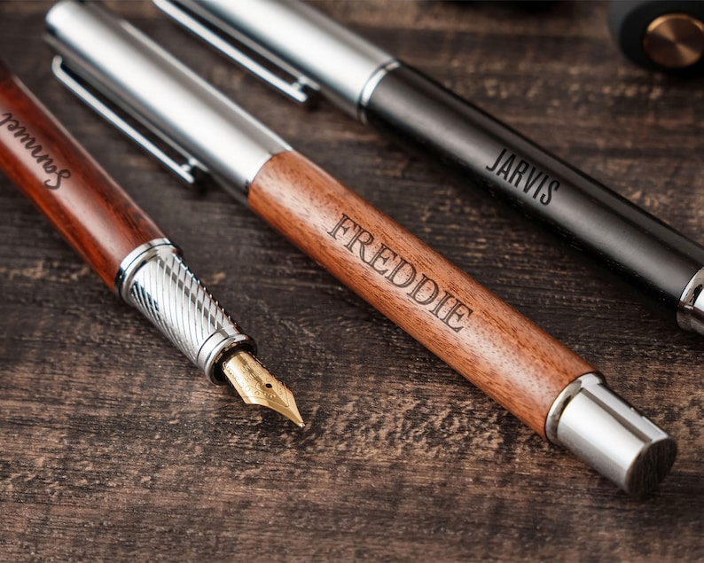three pens and a pen on a wooden table