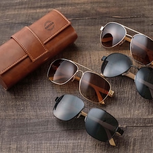 three pairs of sunglasses sitting on a wooden table