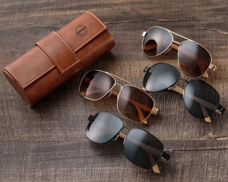 three pairs of sunglasses sitting on a wooden table
