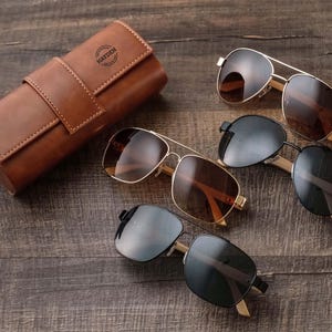 three pairs of sunglasses sitting on a wooden table