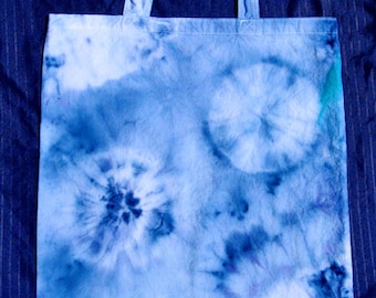 May include: A blue and white tie-dye tote bag with a white canvas base and blue dye in a circular pattern.