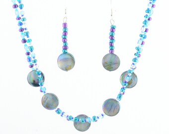May include: A blue and purple beaded necklace with iridescent shell accents and matching earrings. The necklace is double-stranded and has a silver clasp.