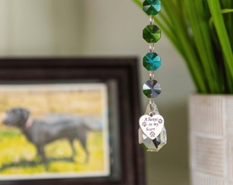 May include: A crystal suncatcher with a heart-shaped charm that reads "Always in my heart" with paw prints on either side. The suncatcher is made of clear crystal beads with green and blue accents.